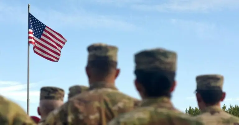 soldiers gathered looking at USA flag